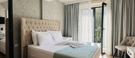 Una habitación de hotel moderna con una cama grande, un área de descanso y un balcón.