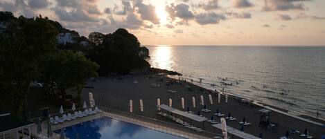 A resort with a swimming pool, beach area, and ocean view.
