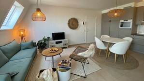 Moderni olohuone, jossa on sohva, sohvapöytä, televisio sekä ruokailutila tuoleineen ja pöytineen.