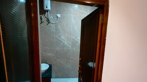 Een badkamer met een glazen deur, een wit wastafelmeubel en een marmeren wand.