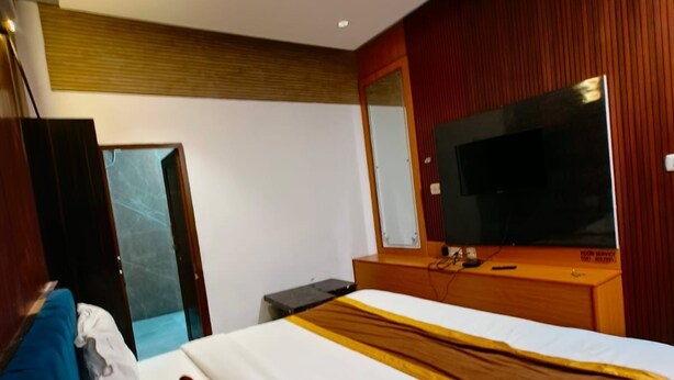 Een hotelkamer met een bed, een televisie, een bureau en een kledingkast.