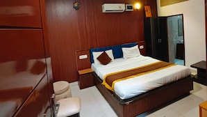 Een hotelkamer met een groot bed, een houten garderobe, een bureau en een stoel.