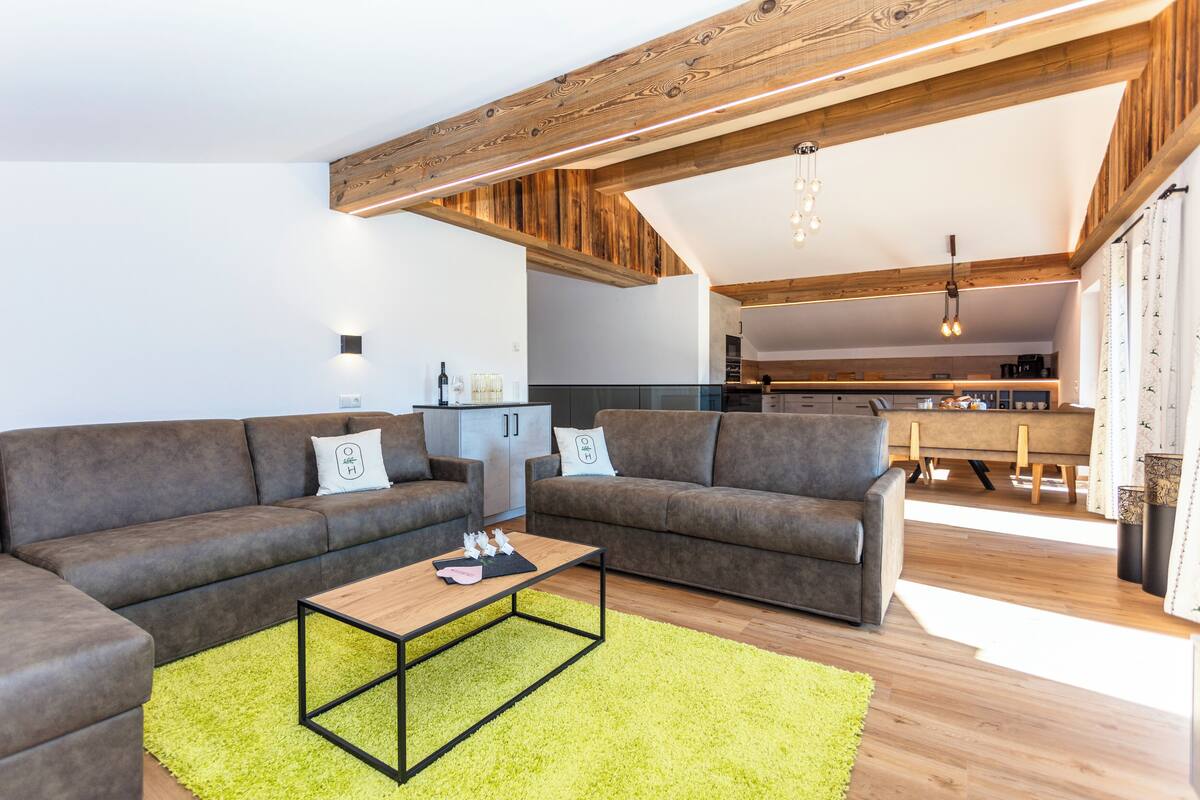 Ein modernes Wohnzimmer mit einem Ecksofa, einem Couchtisch und einem leuchtend grünen Teppich.