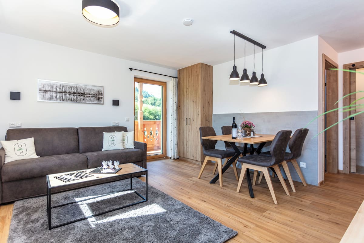 Ein modernes Wohnzimmer mit einer Couch, einem Couchtisch und einem Essbereich mit Stühlen und einem Tisch.
