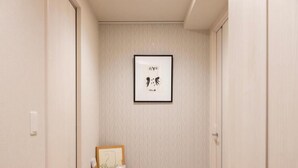 A hallway with a framed artwork on the wall, a small wooden table with a plant, and a door on the right. - Mondomio Sapporo 510 (Sapporo)