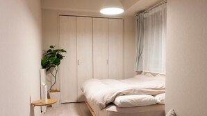 A bedroom with a bed, a wardrobe, a small table, and a potted plant. - Mondomio Sapporo 510 (Sapporo)