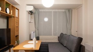 A modern living room with a sofa, a TV, a wooden table, and a ceiling light. - Mondomio Sapporo 510 (Sapporo)
