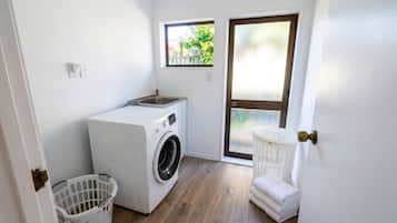A compact laundry room with a washing machine, a drying rack, and a small window.