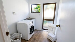 Une petite buanderie équipée d’un lave-linge, d’un étendoir et d’une petite fenêtre.