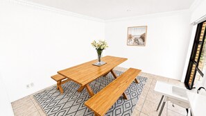 Un coin repas avec une table et des bancs en bois, un vase rempli de fleurs et un tableau encadré accroché au mur.