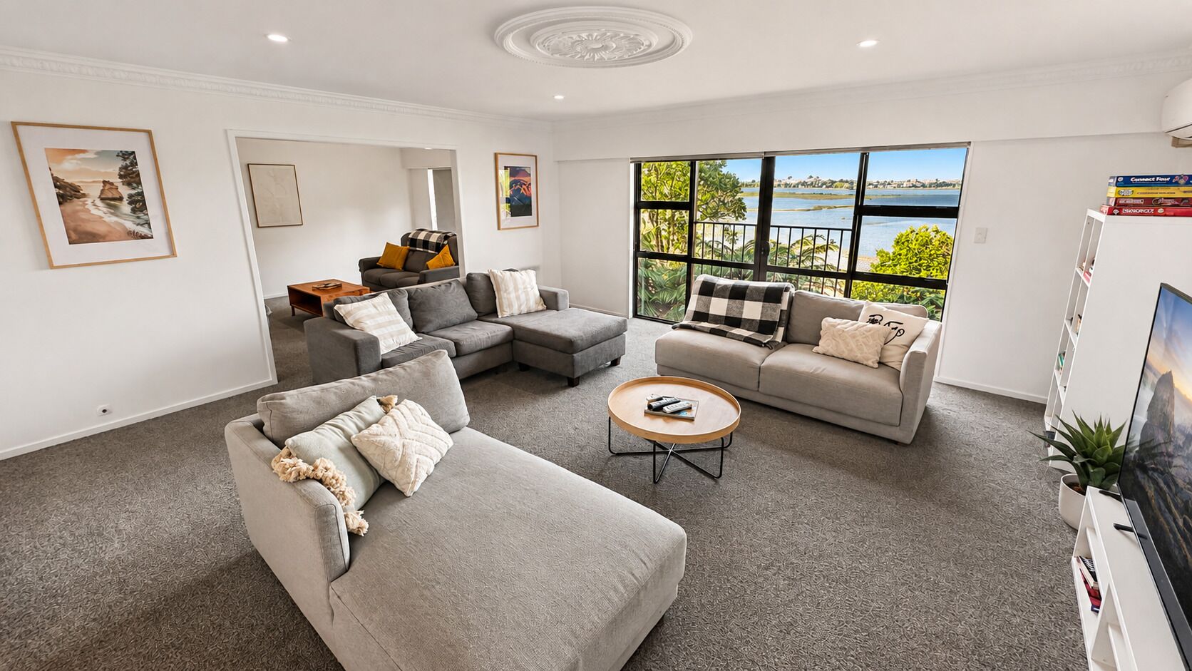 A modern living room with grey sofas, a coffee table, and artwork on the walls.
