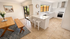 A modern kitchen with a central island, white cabinetry, and a large window.