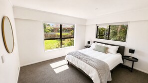 A bedroom with a bed, two bedside tables, a window, and a mirror.