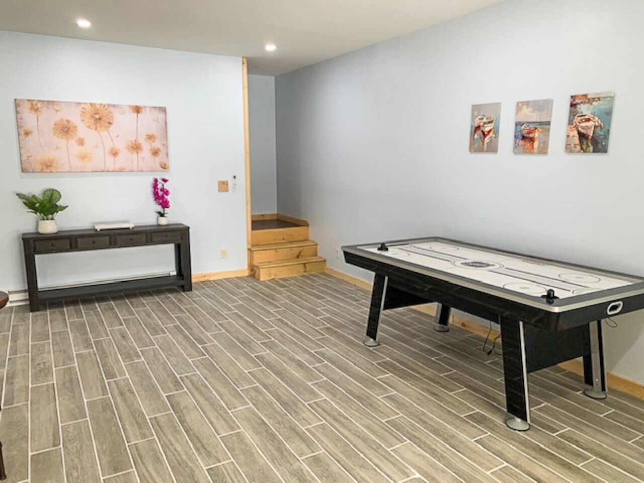 A room with a pool table, a bench, and a staircase.