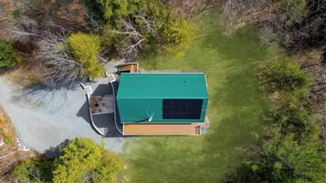 An aerial view of a single-story building with a green roof, surrounded by a well-maintained lawn and dense trees.