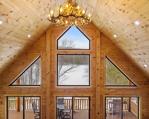 A log cabin with a sloped roof, large windows, and a chandelier.