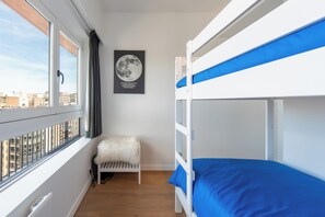 A bunk bed room with a window, a poster on the wall, and a small white furry rug. - Centraal Appartement Voor 4 Personen (Ostend)