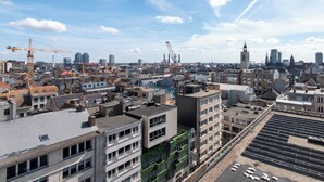 Paesaggio urbano con diversi edifici, tra cui una torre importante e gru edili.