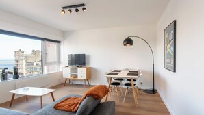 Un soggiorno moderno con un divano, un tavolino, una televisione e un'area pranzo con sedie.