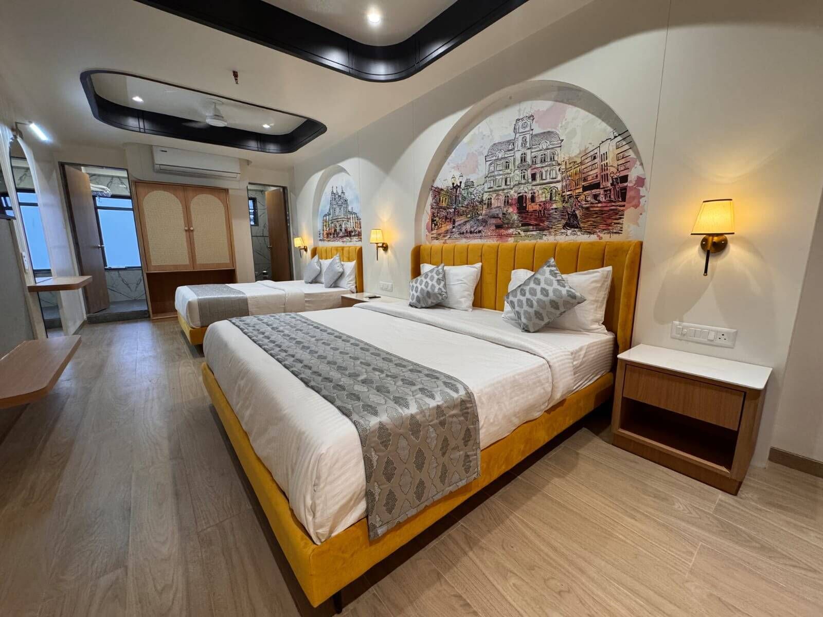 A hotel room with a large bed, two bedside tables, a small desk, and a mural on the wall.