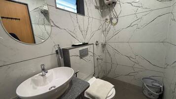 Un baño con lavamanos blanco, toallero, ducha y pared de mármol.