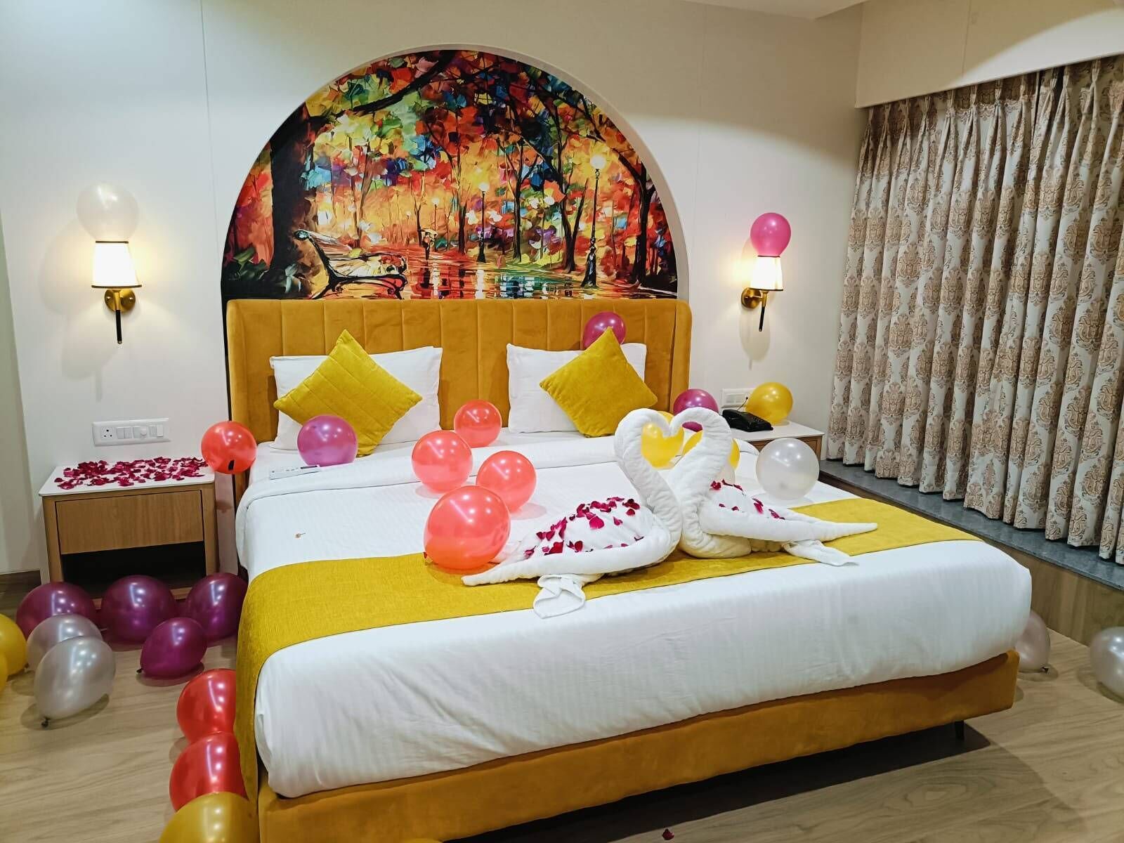 A hotel room with a large bed, a painting above the bed, and a curtain on the window.