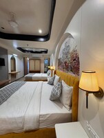 Habitación de hotel con dos camas, una lámpara de pared y un mural.