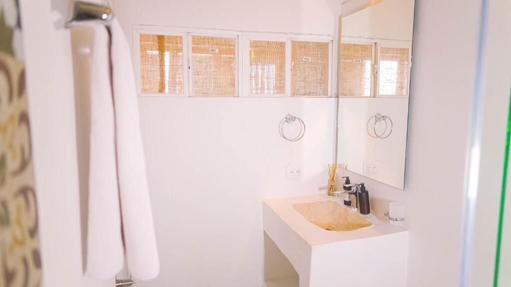 A bathroom with a white sink, mirror, and towel rack.