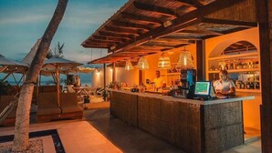 A bar area with a counter, seating, and a view of the ocean.