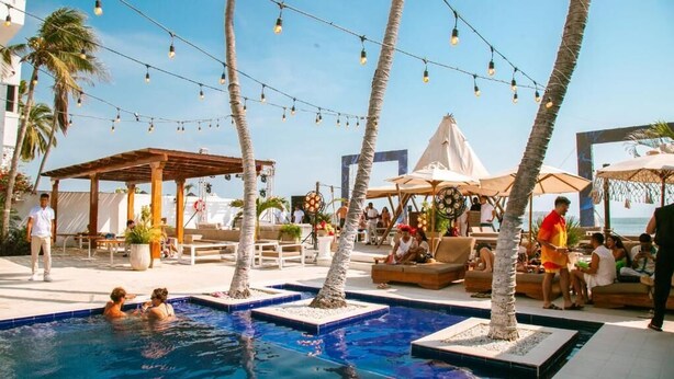 A pool area with lounge chairs, umbrellas, and string lights.