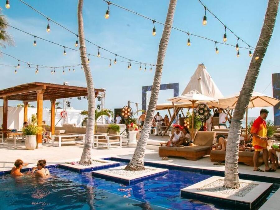 Un espace piscine aménagé avec des chaises longues, des parasols et des guirlandes lumineuses.