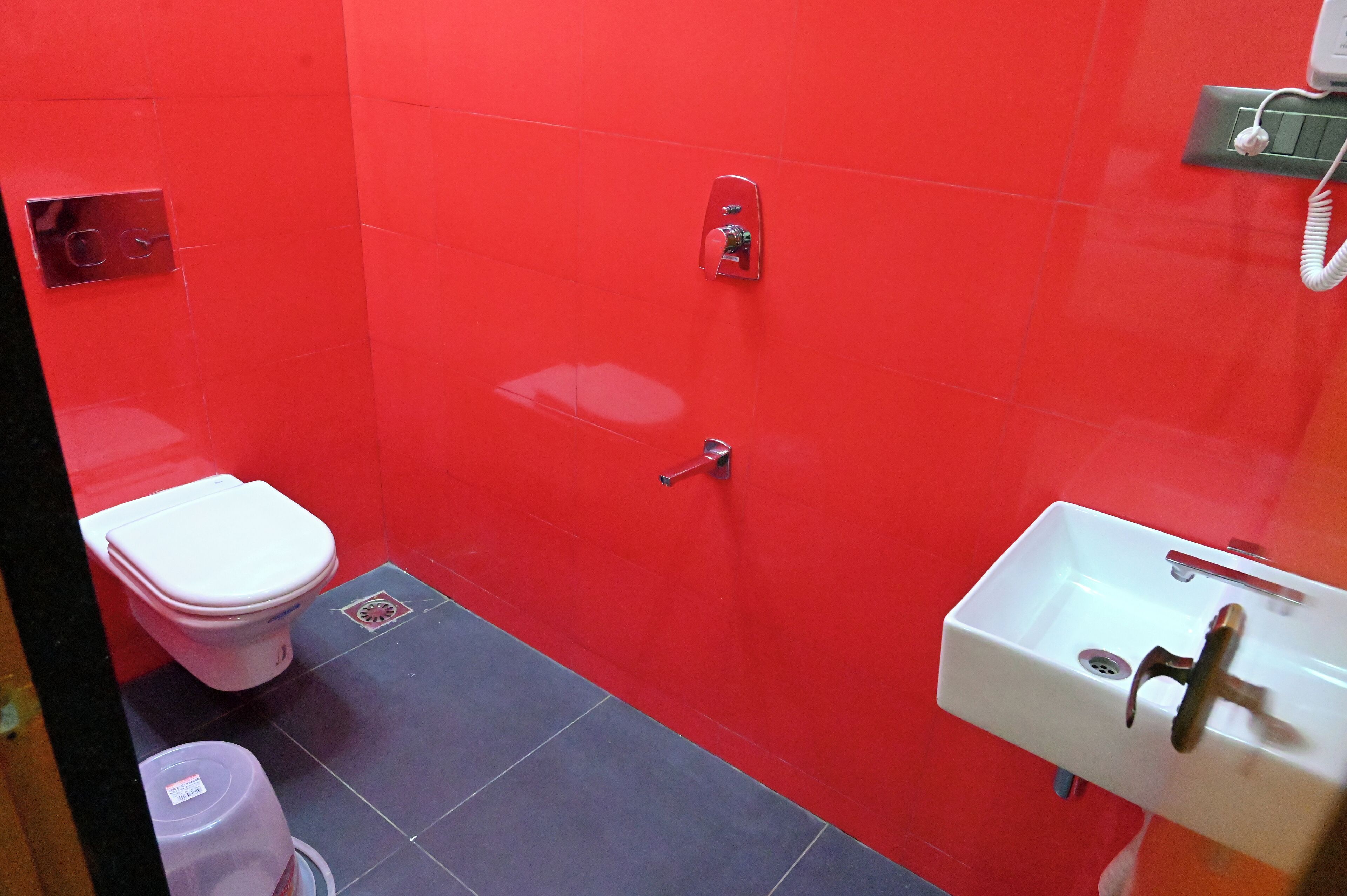 Un baño pequeño con inodoro, lavamanos y paredes de baldosas rojas.