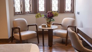 A room with two chairs, a small round table with a vase of flowers, and a bed. - Park Suites (Kolkata)