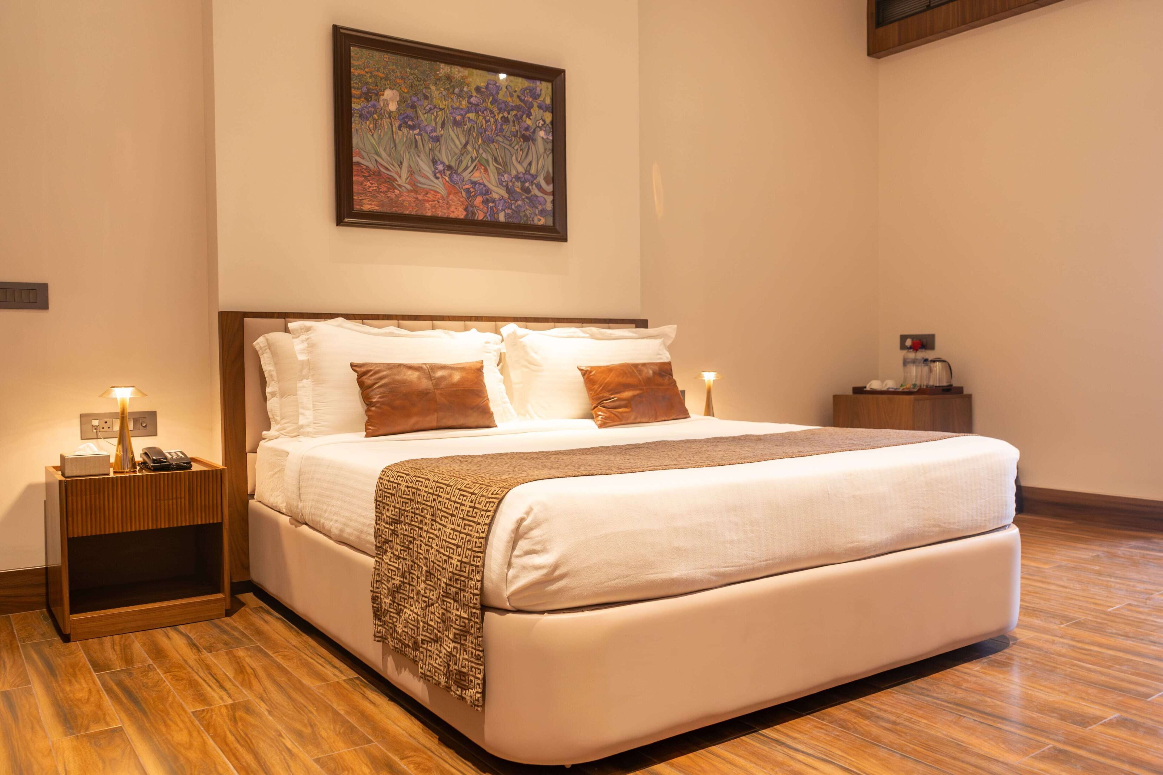 A neatly made bed with a patterned throw, a bedside lamp, and a nightstand with a phone and a small table.