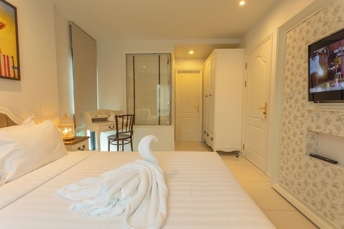 Une chambre d’hôtel comprenant un lit, un bureau, une chaise, une télévision et une armoire.