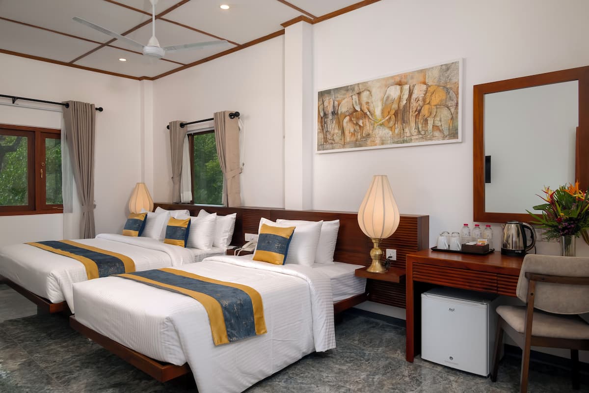 A hotel room with two beds, a desk, a chair, a small fridge, and a painting on the wall.