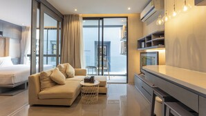 A modern hotel room with a sofa, a small round table, a balcony with a chair, and a desk with shelves. - FullyLoadedBestFacilitiesNicestAptc141 (Kamala)