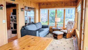 A wooden cabin interior with a sofa, wooden table, and a chair. - Lake Huron Cottage with Private Beach Access, walking distance to Port Sanilac (Port Sanilac)