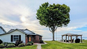 A house with a brick section and a white siding section, a tree, and a gazebo with outdoor seating. - Lake Huron Cottage with Private Beach Access, walking distance to Port Sanilac (Port Sanilac)