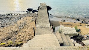 A concrete staircase leading to a pier extending into calm water, surrounded by pebbles and sand. - Lake Huron Cottage with Private Beach Access, walking distance to Port Sanilac (Port Sanilac)