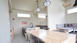 Una cocina moderna con comedor, un sofá gris con cojines coloridos y una mesa de madera.