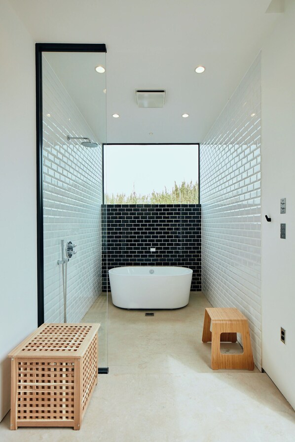 A modern bathroom with a freestanding bathtub, a wooden stool, and a small wooden crate. - THE CHIKURA UMI BASE CAMP (Minamiboso)