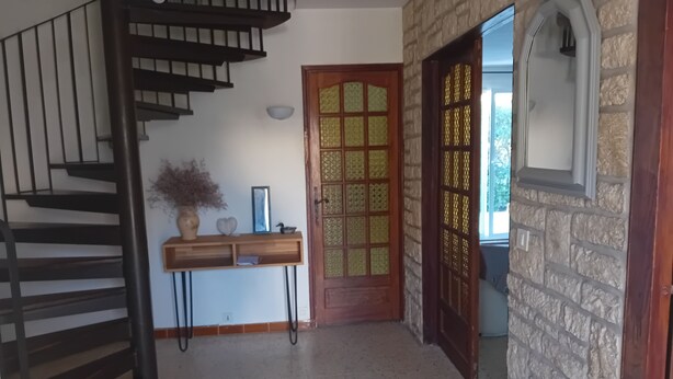 A staircase leading to a landing with a wooden console table, a decorative door, and a stone wall. - Large house in Provence village of Entressen with enclosed garden planted with trees, quiet location (Istres)