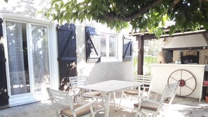 An outdoor patio with a table and chairs, a grill, and a covered seating area. - Large house in Provence village of Entressen with enclosed garden planted with trees, quiet location (Istres)