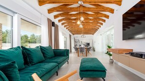 A modern living room with a green sofa, wooden coffee table, and a TV mounted on the wall. - Villa Olea Pridraga ZadarVillas (Pridraga)
