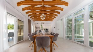 A spacious dining area with a wooden ceiling, large windows, and a modern chandelier. - Villa Olea Pridraga ZadarVillas (Pridraga)