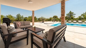 Un espace extérieur abrité comprenant une piscine, des sièges et un barbecue.