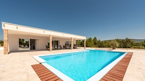 Une maison moderne dotée d’une piscine, d’un patio couvert et offrant une vue sur la campagne.