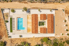 Eine Vogelperspektive eines Resorts mit Swimmingpool, Liegestühlen und einer überdachten Terrasse.