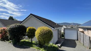 A residential house with a garage, neatly trimmed hedges, and a clear sky.
